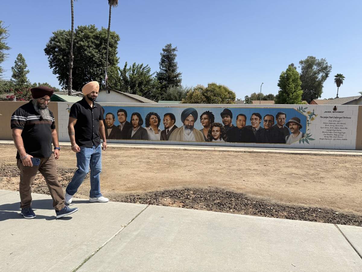 Sikh men walk in front of murals depicting Jaswant Singh Khalra and other human rights activists in Fresno.